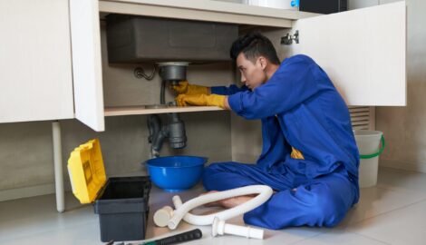 plumber-blue-overalls-clearing-blockage-drain-scaled
